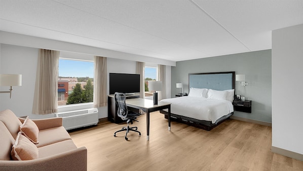 Una habitación de hotel moderna con una cama grande, un escritorio, una silla y un televisor.
