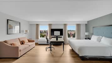 Et hotelværelse med seng, skrivebord, stol, sofa og fjernsyn.