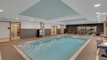 A swimming pool with a shallow area, lounge chairs, and a seating area with tables.