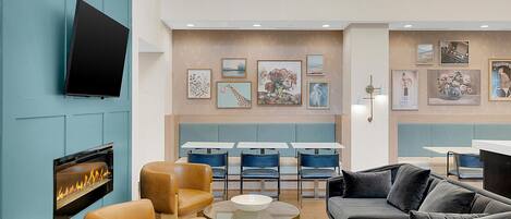 A modern lounge area with a fireplace, comfortable seating, and artwork on the walls.