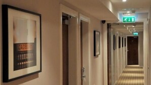 A hotel hallway with framed artwork on the walls, a carpeted floor, and doors leading to rooms. - The Royal George Hotel (Birmingham)