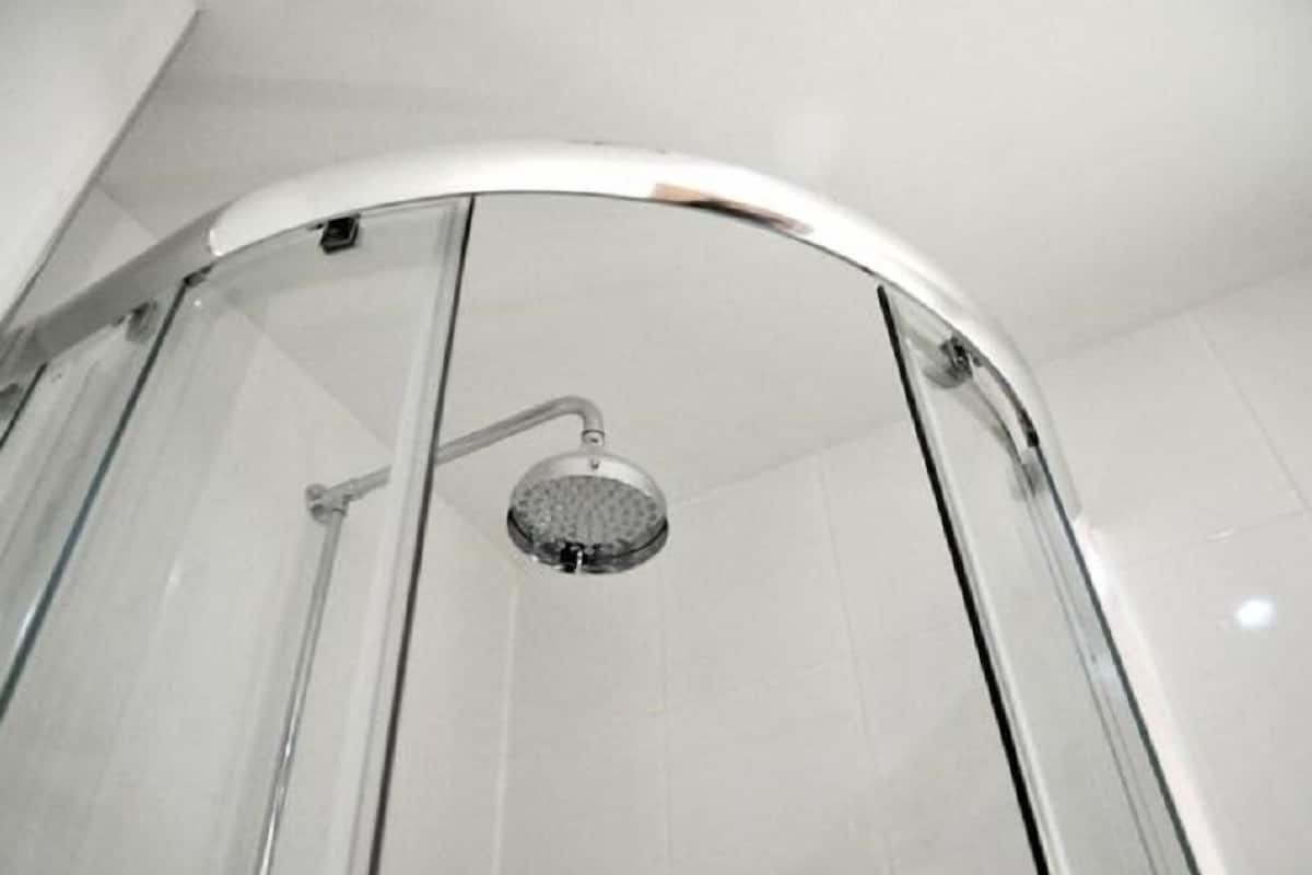 A glass-enclosed shower with a handheld showerhead.
