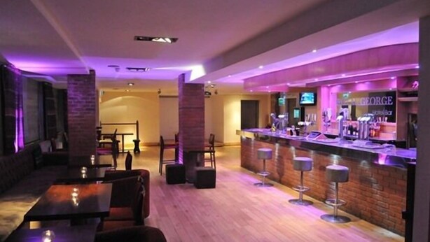 A bar area with a counter, stools, and a seating area with tables and chairs. - The Royal George Hotel (Birmingham)