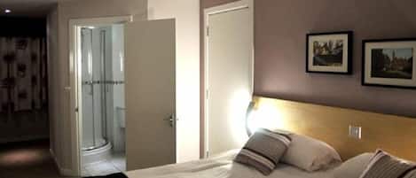 Ein Schlafzimmer mit einem Bett, einer Nachttischlampe und einer Tür zu einem Badezimmer.