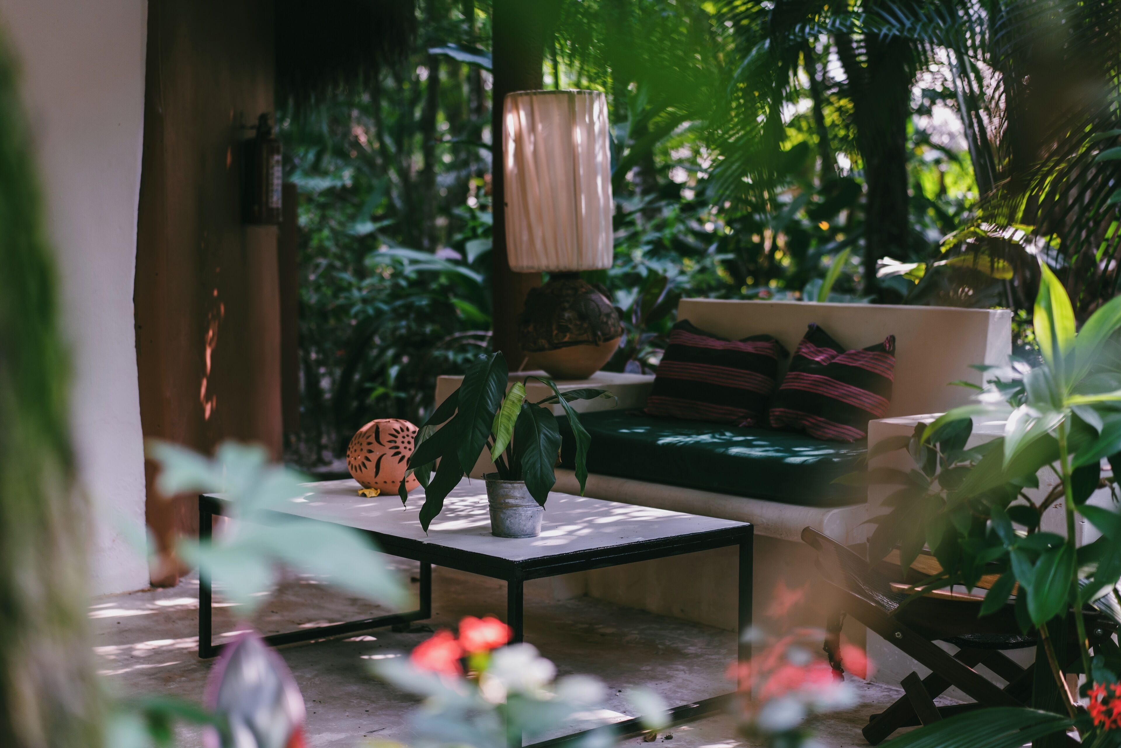 Un rincón al aire libre acogedor con una mesa, un sofá y varias plantas.