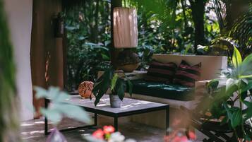 Un rincón al aire libre acogedor con una mesa, un sofá y varias plantas.