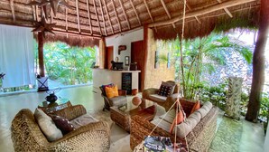 A spacious room with wicker furniture, a reception desk, and a view of lush greenery. - Piedra de Agua Hotel Boutique Palenque (Palenque)