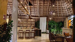 A thatched-roof bar area with wooden chairs and a bar counter. - Piedra de Agua Hotel Boutique Palenque (Palenque)