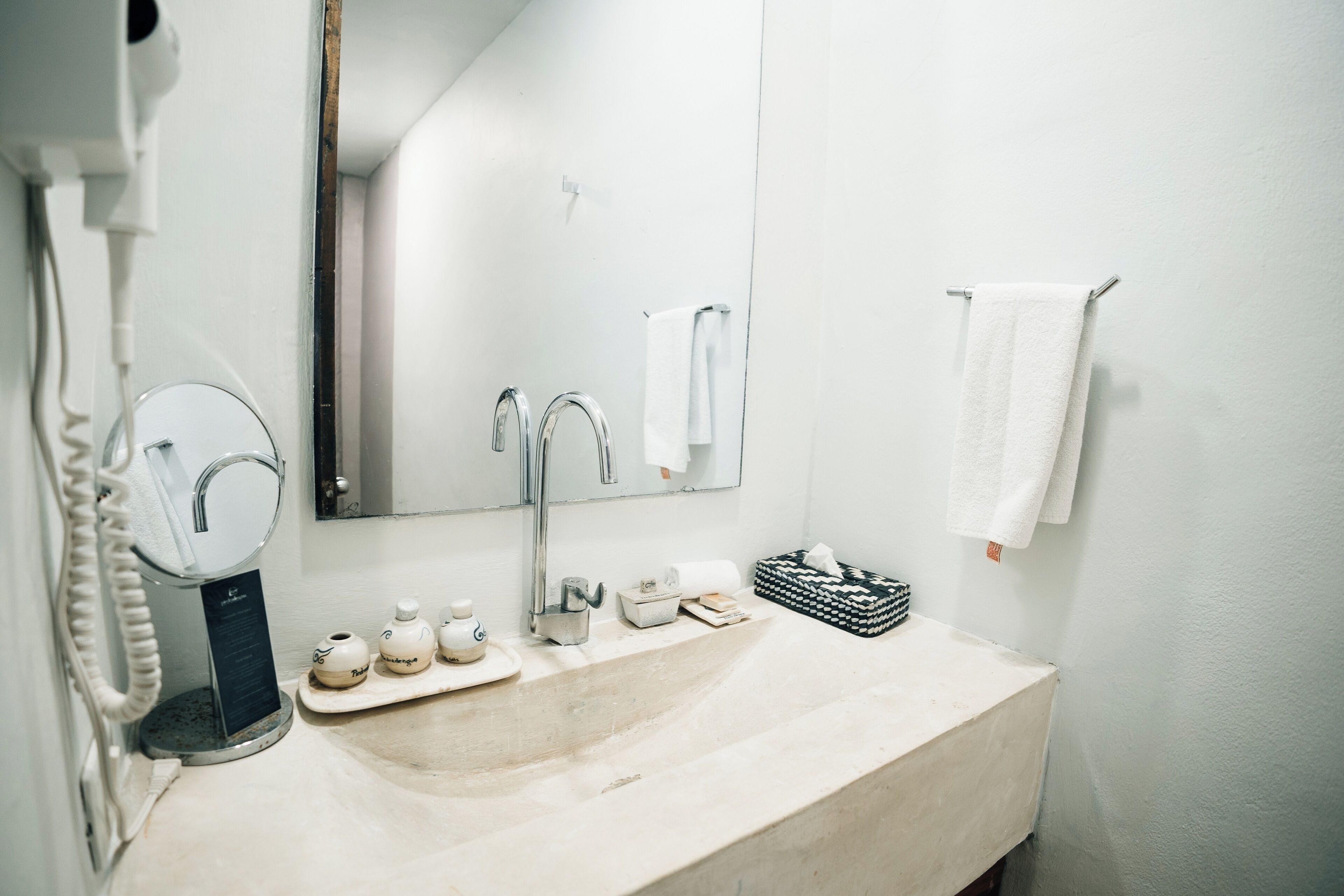 A bathroom with a sink, mirror, towel rack, and a hairdryer.