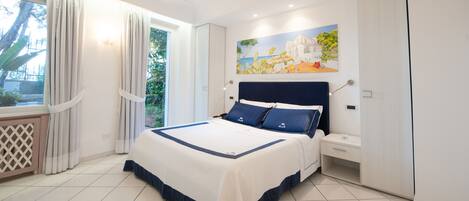 A bedroom with a large bed, a nightstand, a wardrobe, and a painting on the wall.