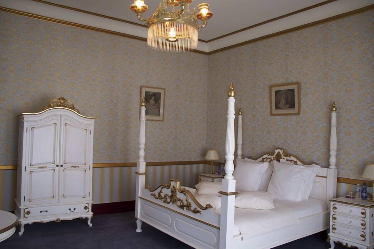 A four-poster bed with a canopy, a white wardrobe, and a nightstand with a lamp.