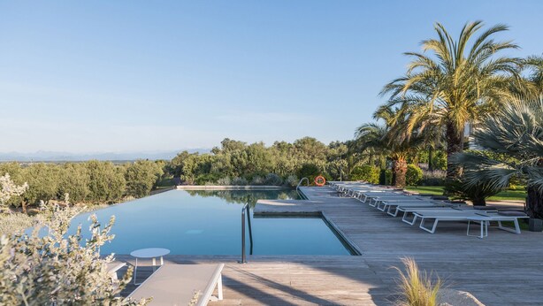 Un área de piscina con sillones de descanso y una terraza de madera.