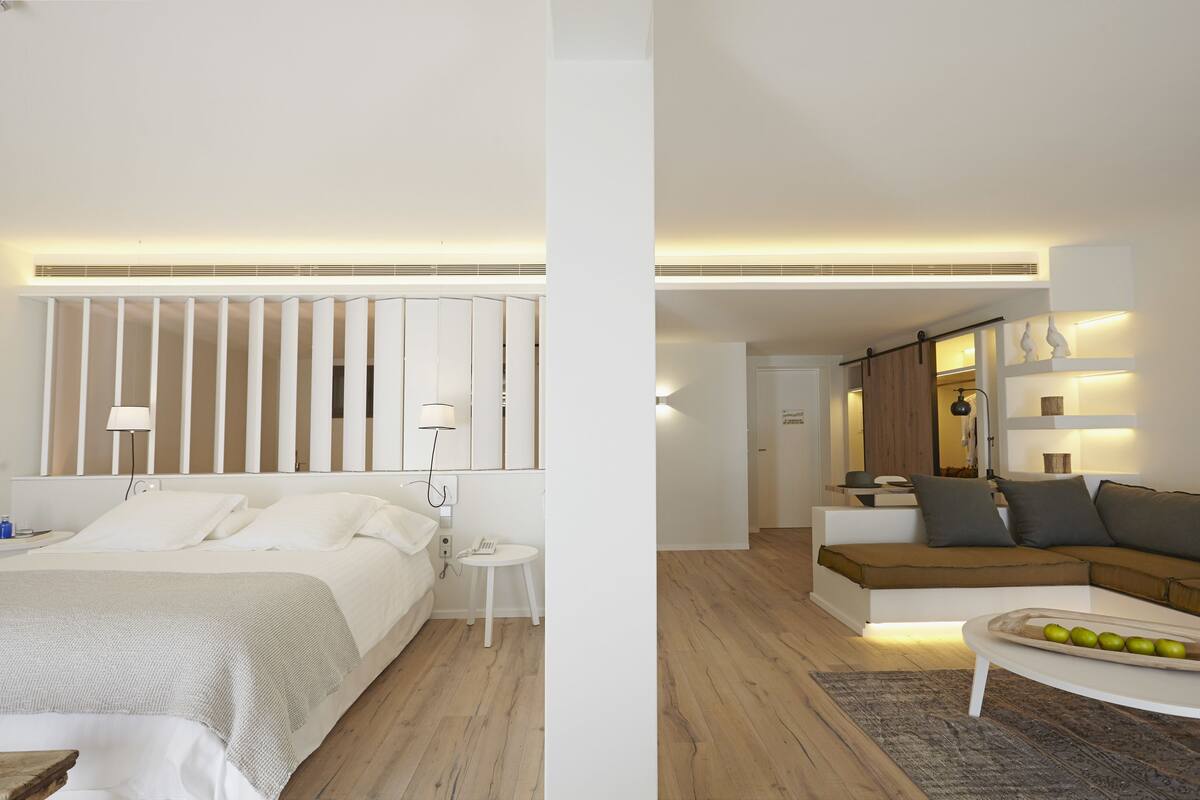 Une chambre d’hôtel moderne équipée d’un lit, d’une table de chevet et d’un coin salon avec un canapé et une table basse.