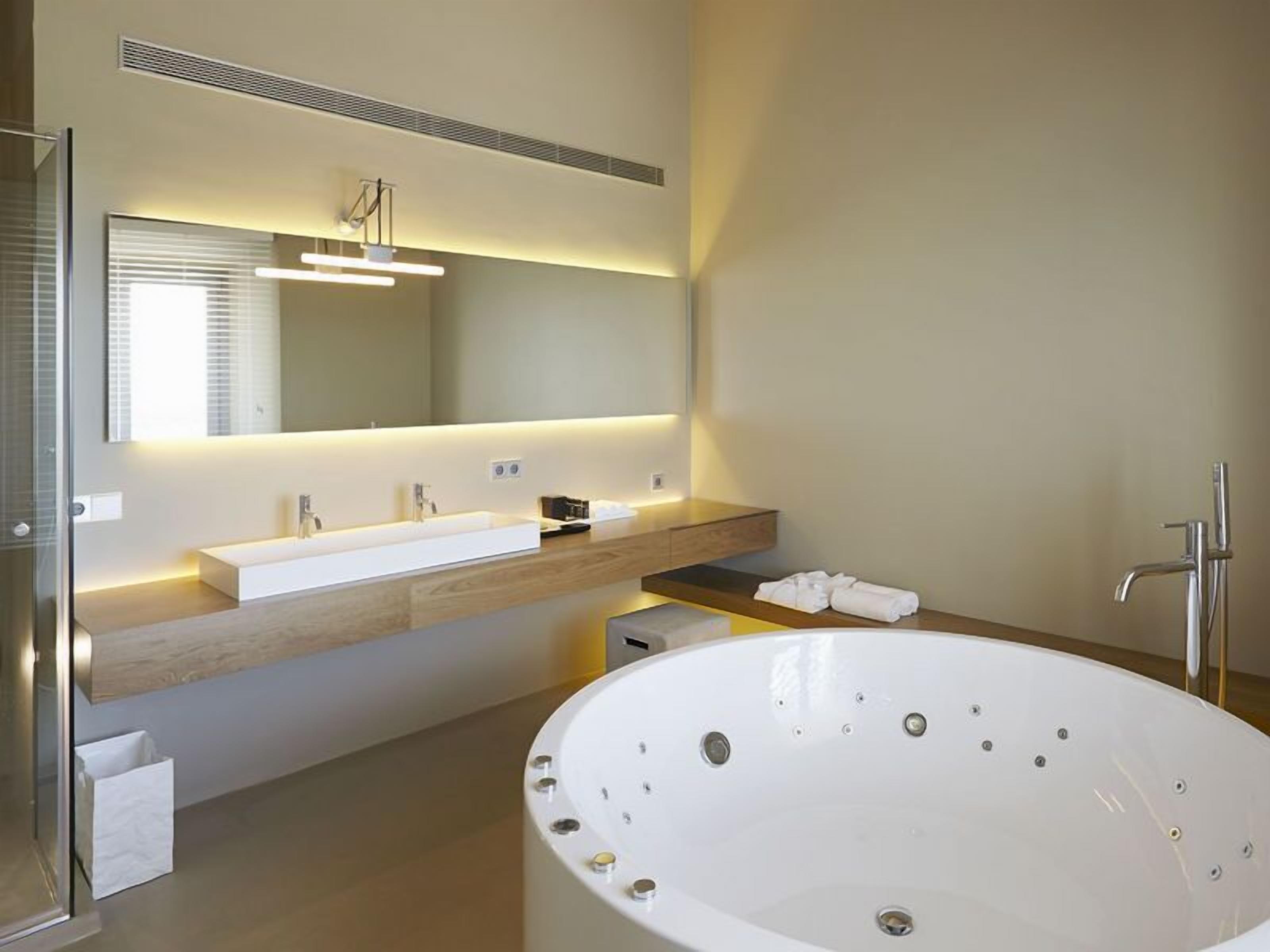 Ein modernes Badezimmer mit einer großen Badewanne, einem Doppelwaschtisch und einem großen Spiegel.