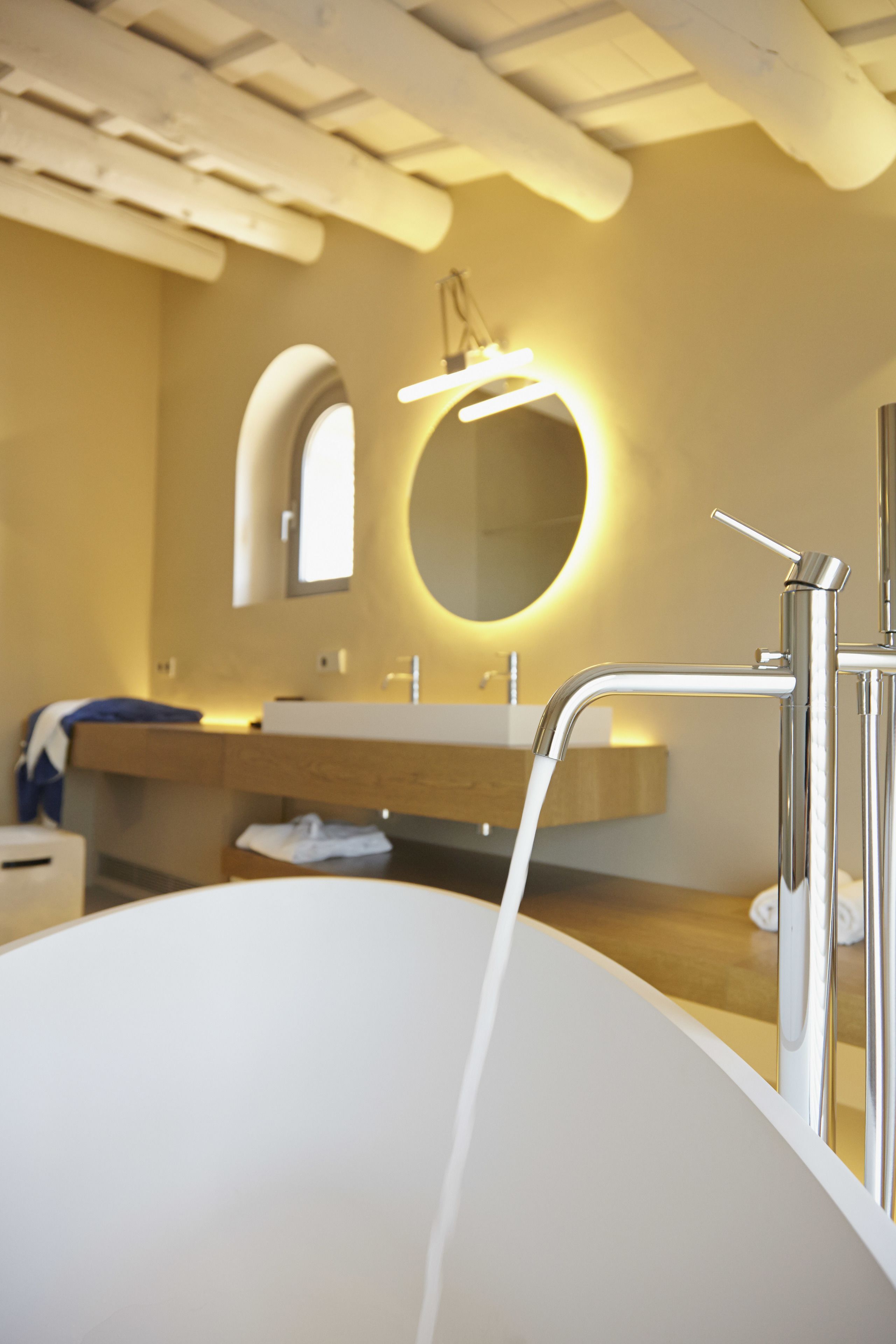 Un baño moderno con una bañera independiente, un tocador con espejo y una lámpara de pared.