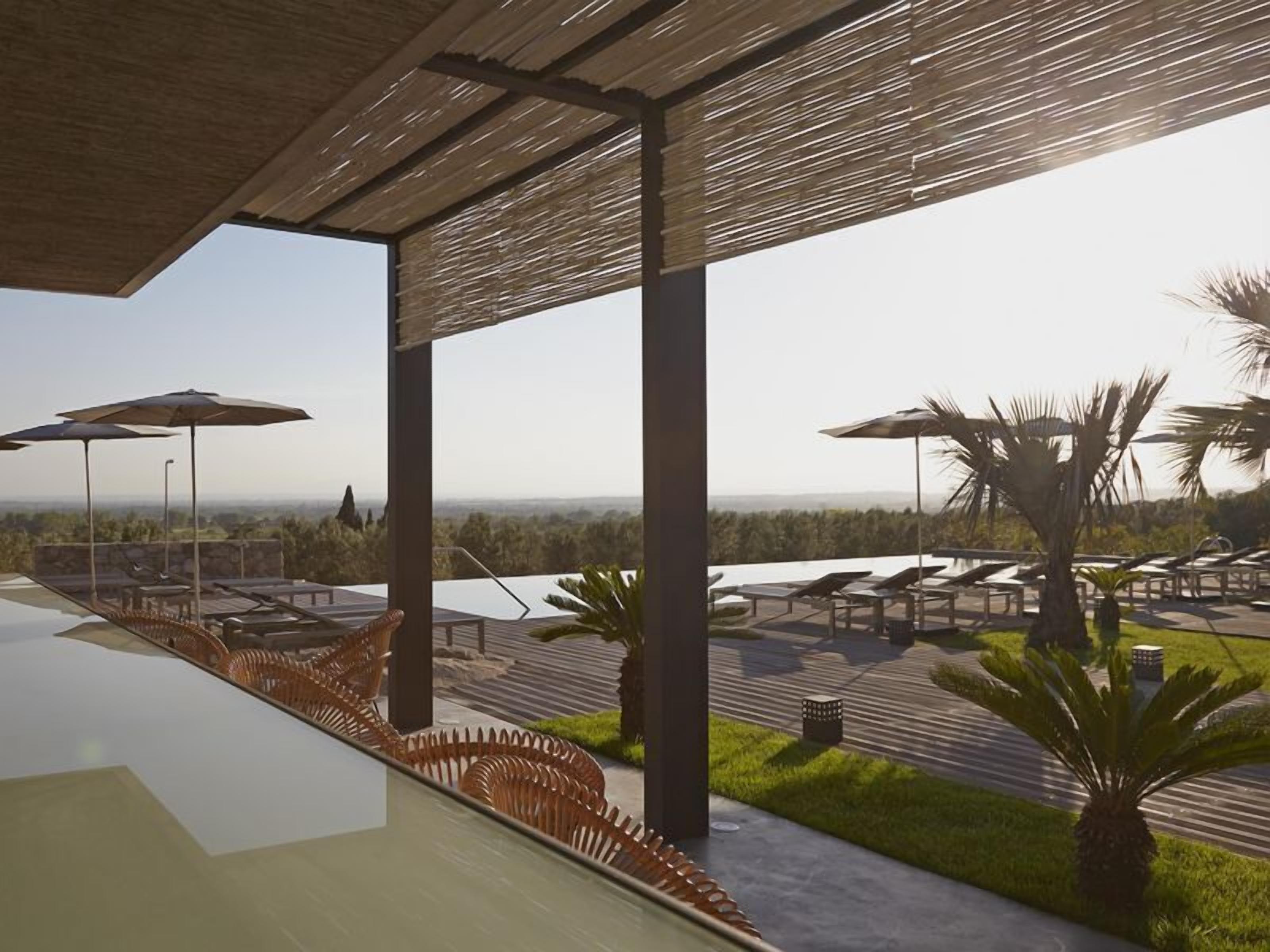 Un espace de détente extérieur moderne, doté de chaises longues et de parasols, offrant une vue imprenable sur un paysage magnifique.