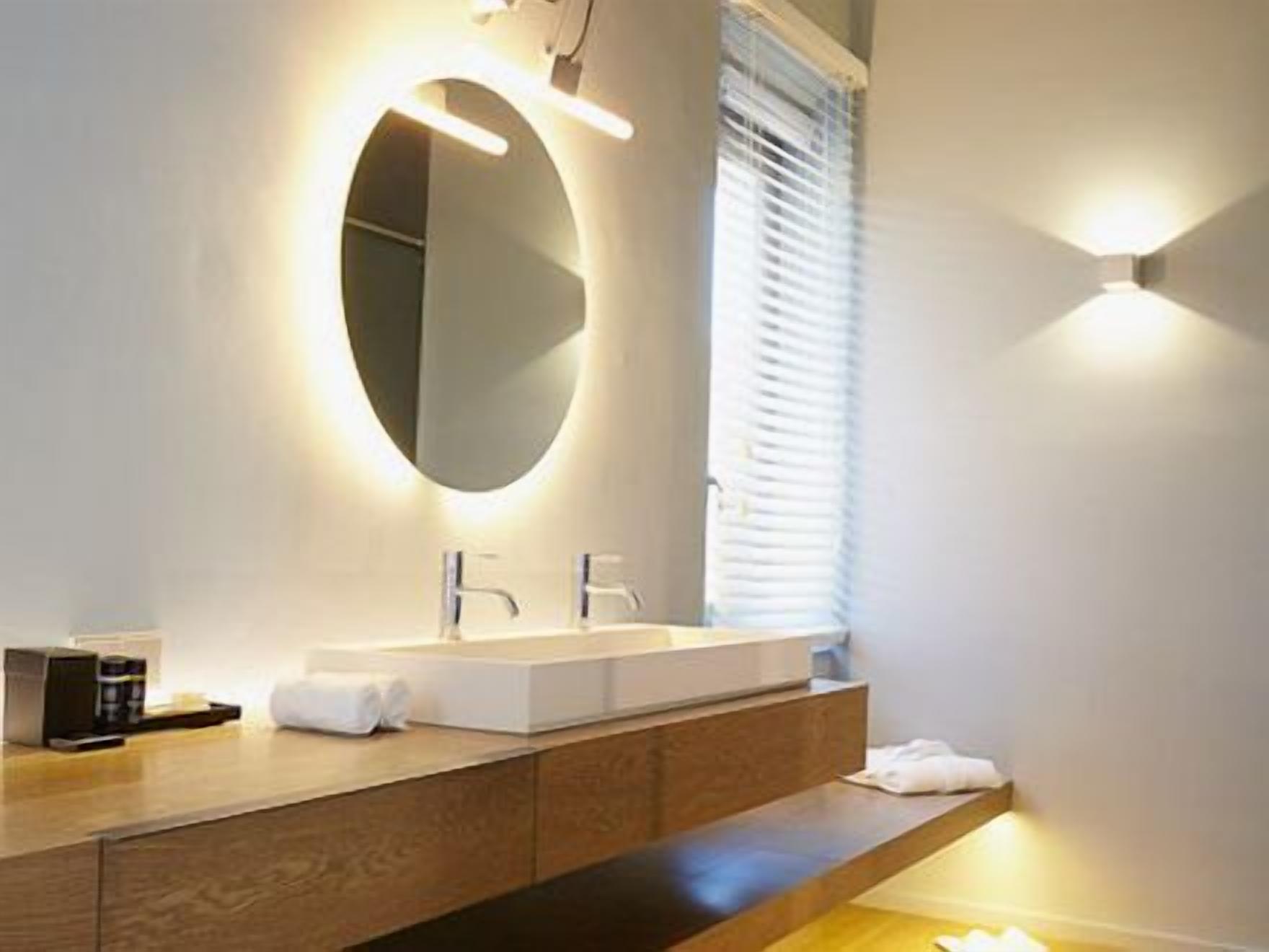 A modern bathroom with a large mirror, a wooden vanity, and a built-in sink.