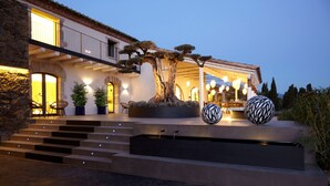 Una casa moderna con fachada de piedra, un árbol grande y una escalera que lleva a la entrada.