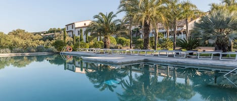 Una piscina al aire libre, sombrillas, tumbonas