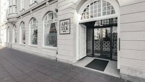 L’entrée d’un hôtel, avec une façade classique, de grandes fenêtres en arc de cercle et une enseigne bien visible.