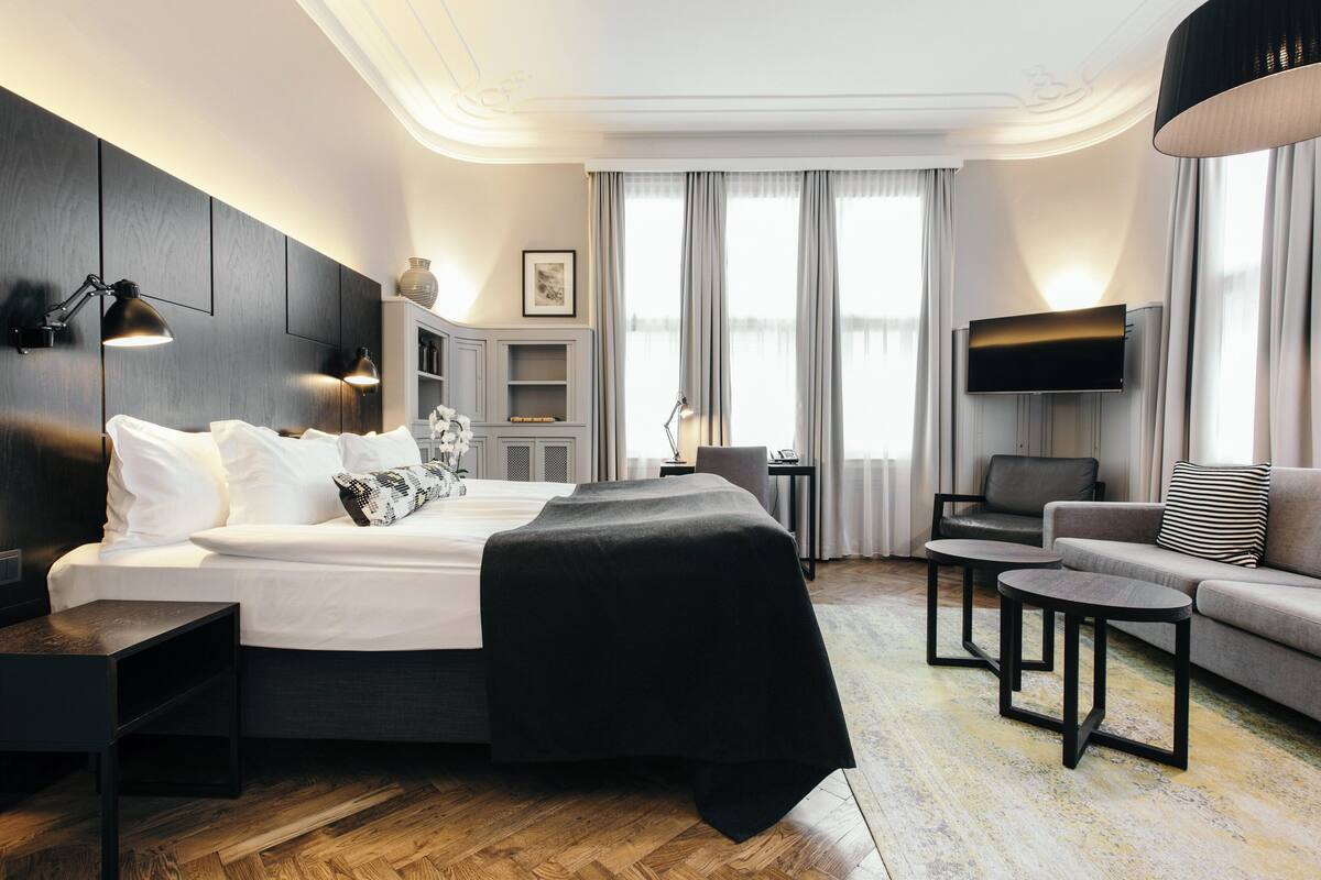 Ein modernes Hotelzimmer mit einem großen Bett, einer Couch, einem Fernseher und einem Schreibtisch.