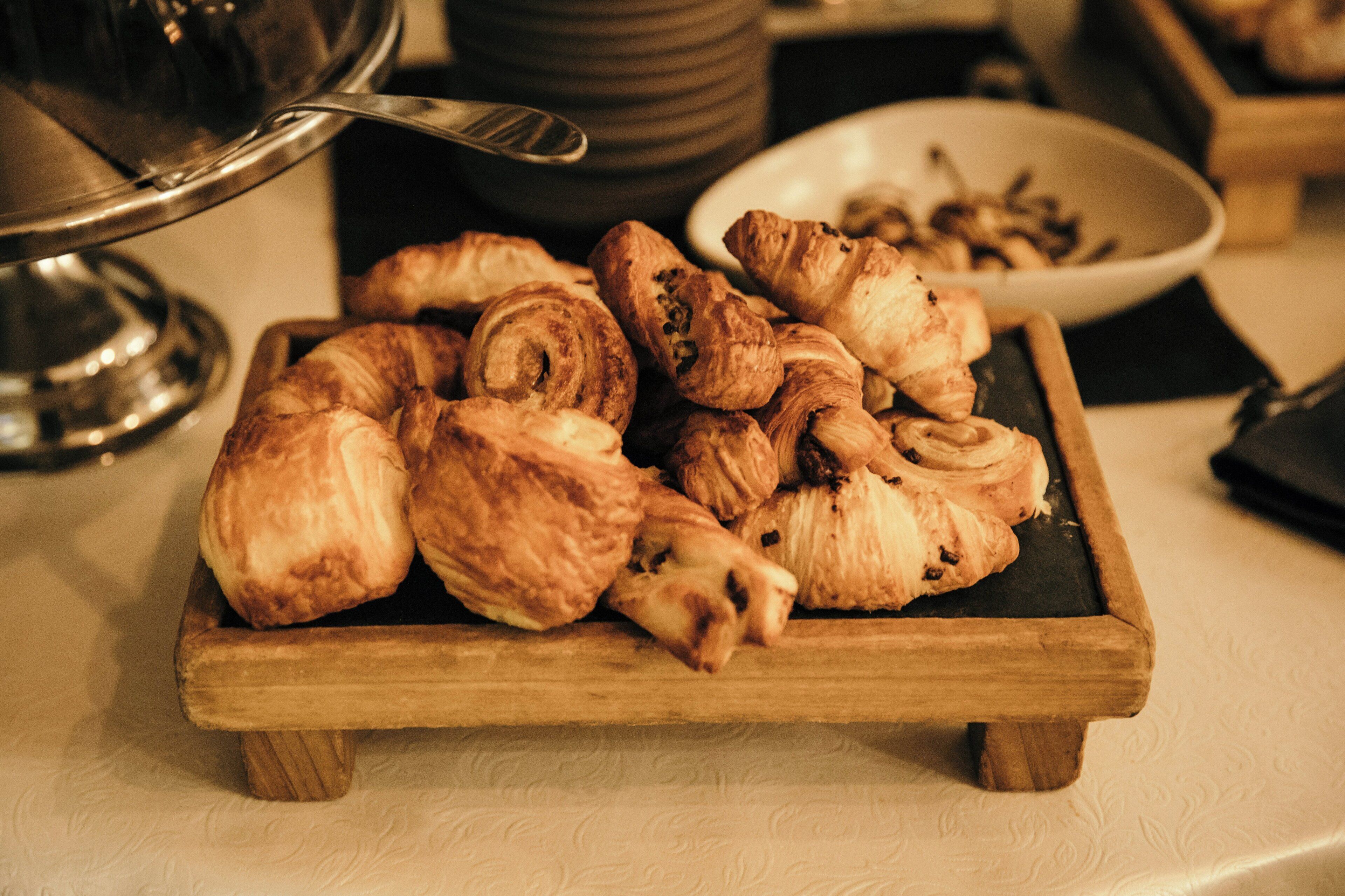 Un plateau de service en bois, sur lequel sont disposées diverses pâtisseries, est posé sur une table.