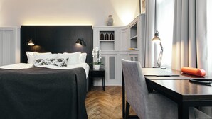 A modern hotel room with a bed, desk, chair, and a small side table with a lamp and a plant. - Apotek Hotel by Keahotels (Reykjavik)