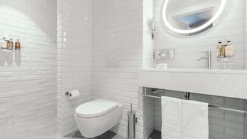 Un baño moderno con azulejos blancos tipo metro, un inodoro, un bidé, un lavabo con espejo y un perchero para toallas.