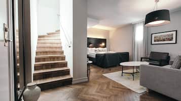 A modern living room with a staircase, a sofa, a coffee table, and a dining area.