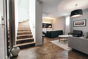 Een moderne woonkamer met een trap, een bank, een salontafel en een eethoek.