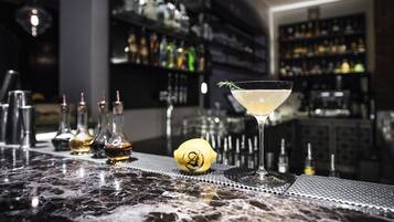 Eine Bar mit Martini-Glas, einer Zitrone und verschiedenen Flaschen auf einer Marmorplatte.