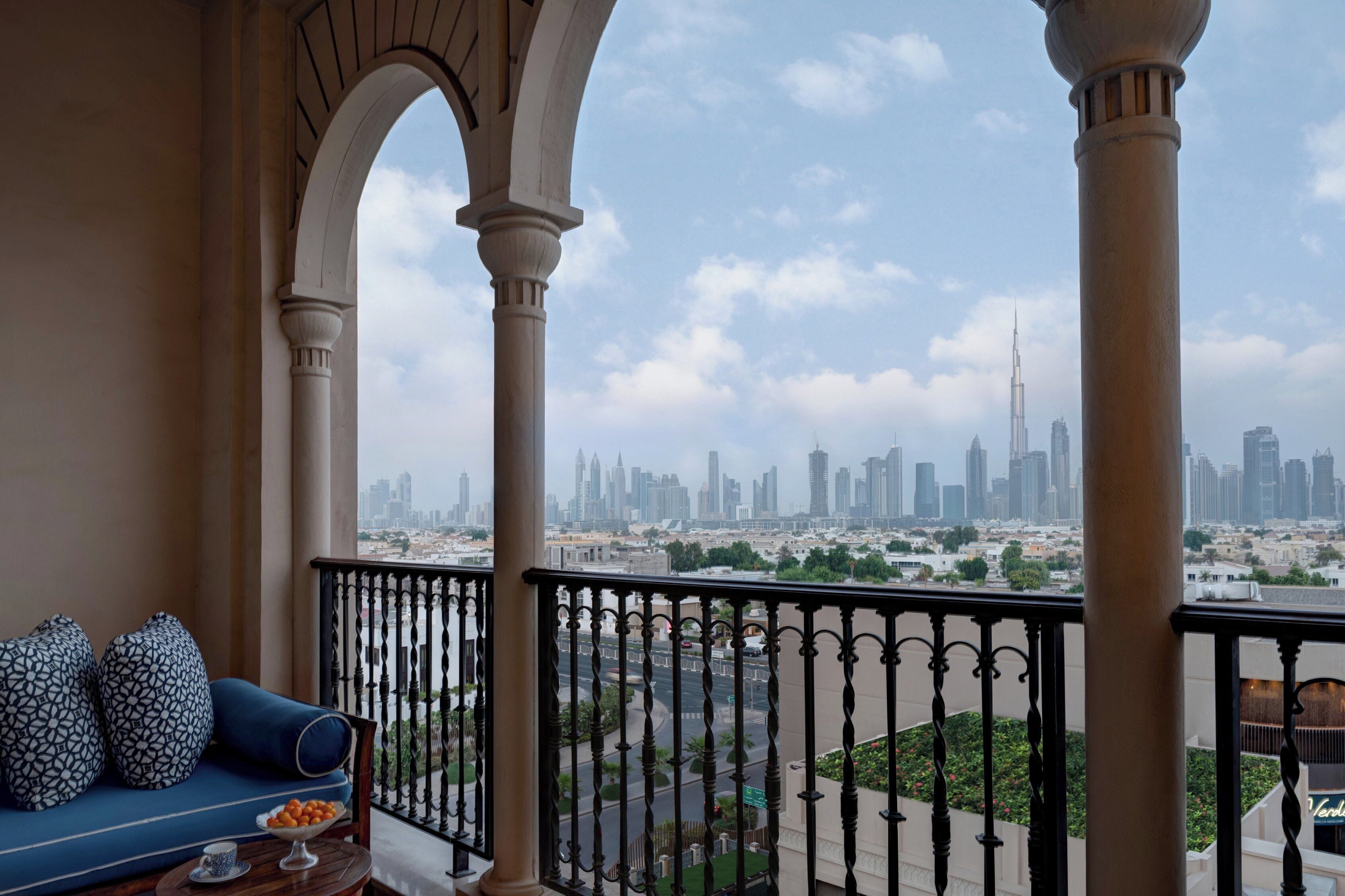 Un balcón con vista a un horizonte urbano, destacándose un rascacielos.