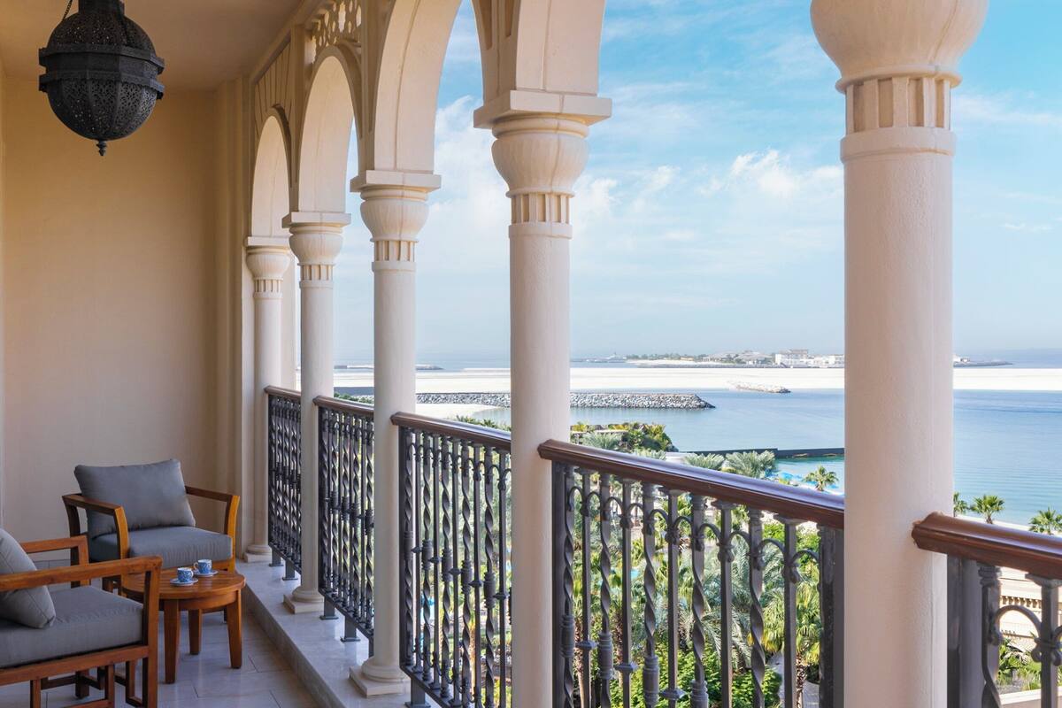 A balcony with a view of the sea, featuring white columns and a railing.