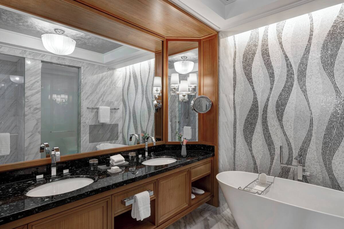 A modern bathroom with two sinks, a freestanding bathtub, and a large mirror.