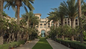 A building with a central entrance, flanked by palm trees and a well-maintained lawn. - Four Seasons Resort Dubai at Jumeirah Beach (Dubai)