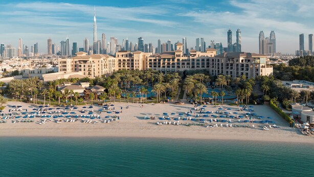 A beachfront hotel with a pool, palm trees, and a city skyline in the background. - Four Seasons Resort Dubai at Jumeirah Beach (Dubai)