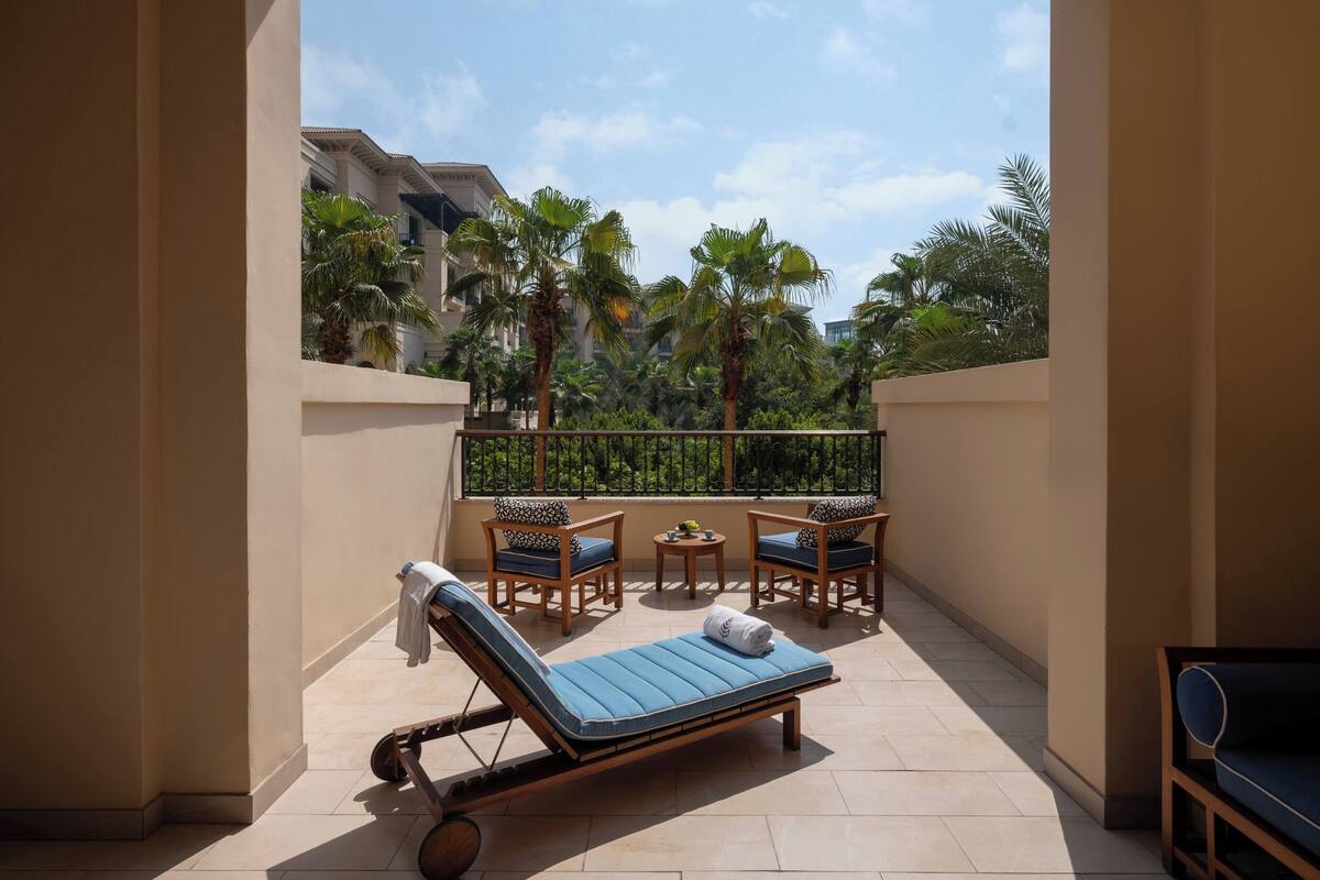 A sunlit balcony with a lounge chair, a small table, and a sofa.