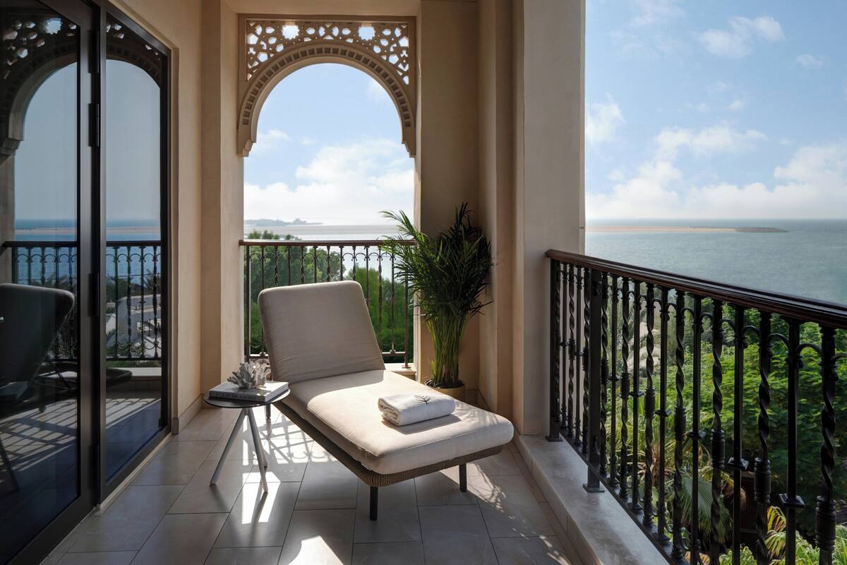A balcony with a cushioned chair, a small table, and a potted plant.