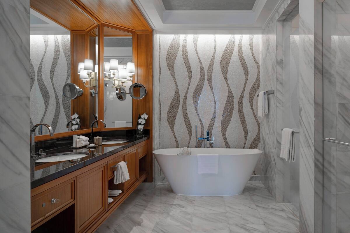 A modern bathroom with a freestanding bathtub, a vanity with a mirror, and a shower area.