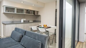 Eine moderne Küche mit Essbereich, grauem Sofa und Blick durch eine Glastür.