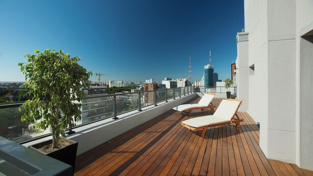 Eine Dachterrasse mit Holzboden, zwei Liegestühlen und einem Blumentopf.