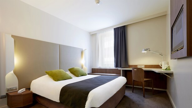 Ein modernes Hotelzimmer mit einem großen Bett, einem Schreibtisch und einem Sessel.