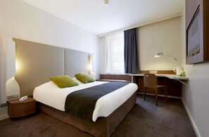Una habitación de hotel moderna con una cama grande, un escritorio y una silla.