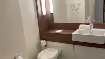 Een badkamer met een wit toilet, een wastafel, een spiegel en een handdoek aan de muur.