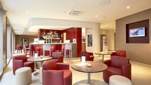 Ein moderner Lounge-Bereich mit roten Sitzgelegenheiten, einer Bar und einem Fernseher.