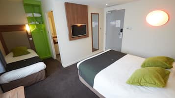 Ein Hotelzimmer mit zwei Einzelbetten, einem grünen Kleiderschrank, einem Flachbildfernseher und einer Tür mit einer Lampe darüber.
