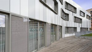 Ein modernes Gebäude mit großen Glasfenstern und einer Holzterrasse.