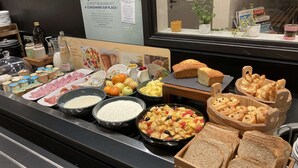 Ein Frühstücksbuffet mit verschiedenen Speisen und einem Schild auf Französisch.