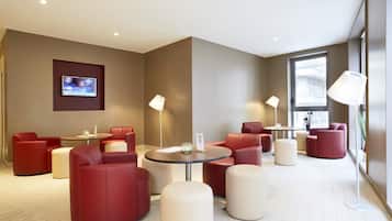 A modern lounge area with red and beige seating, a flat-screen TV, and ambient lighting.