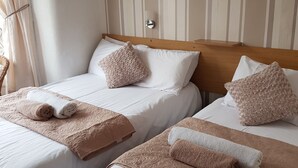 Habitación de hotel con dos camas, cada una con cabecero de madera, ropa de cama blanca y almohadas decorativas.